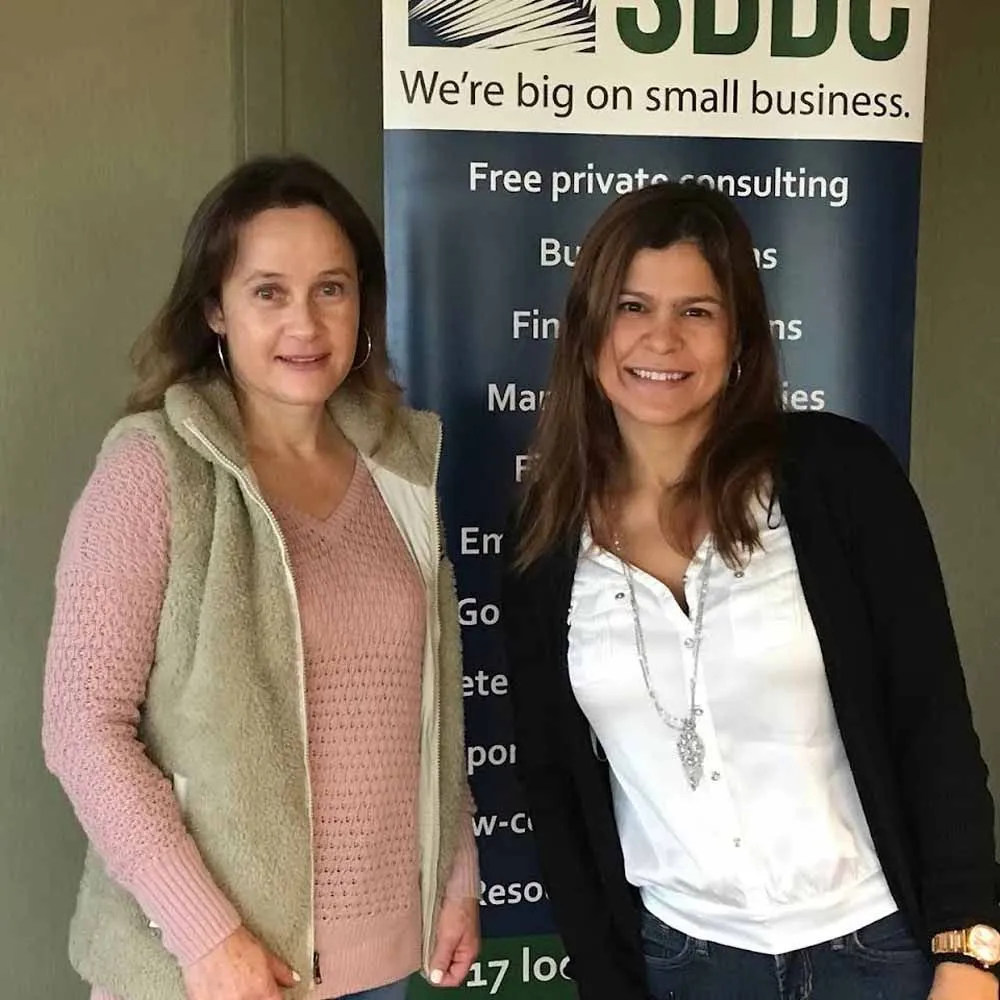 Two women standing in front of a sign that says we 're big on small business