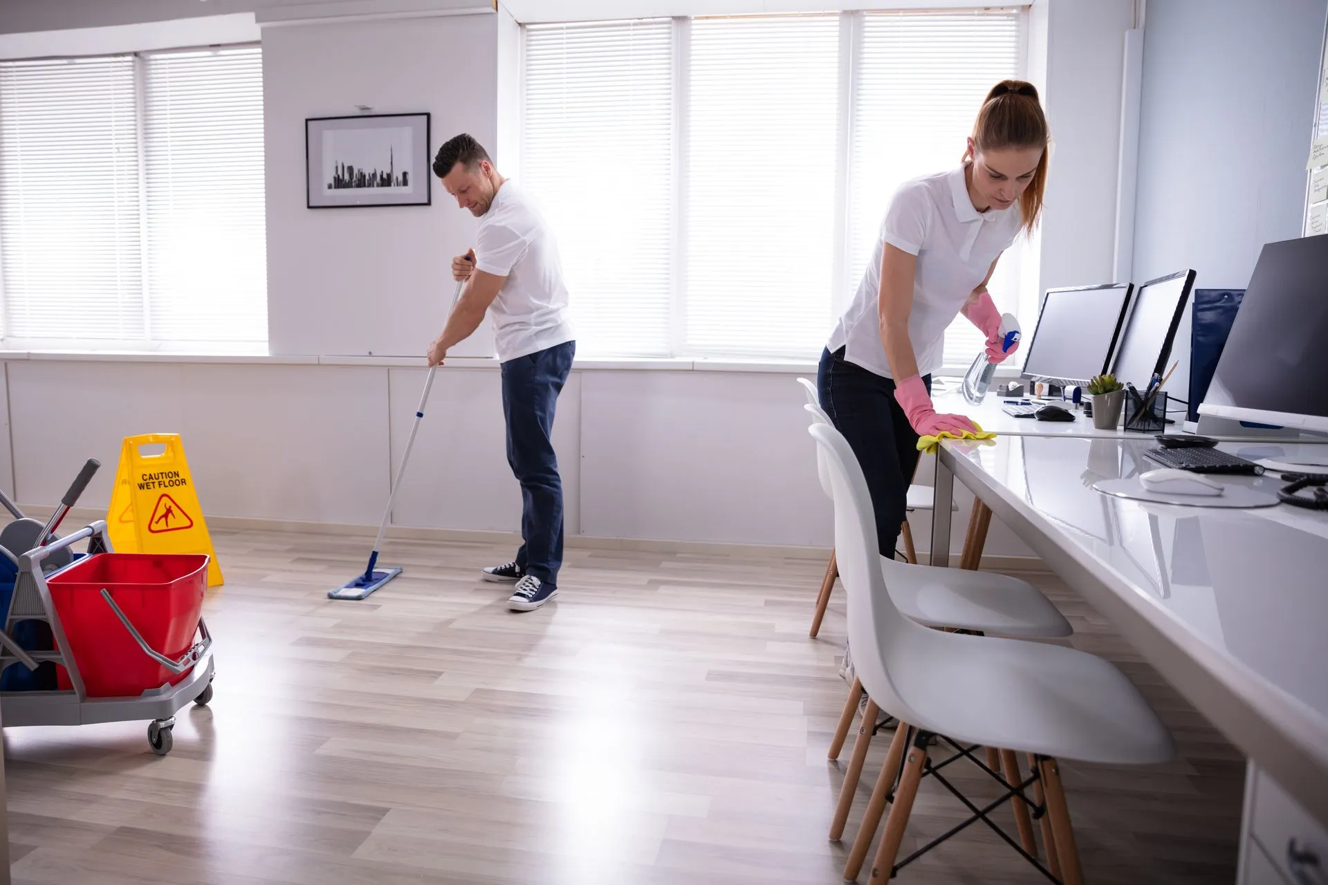 A man and a woman are cleaning the floor of an office.