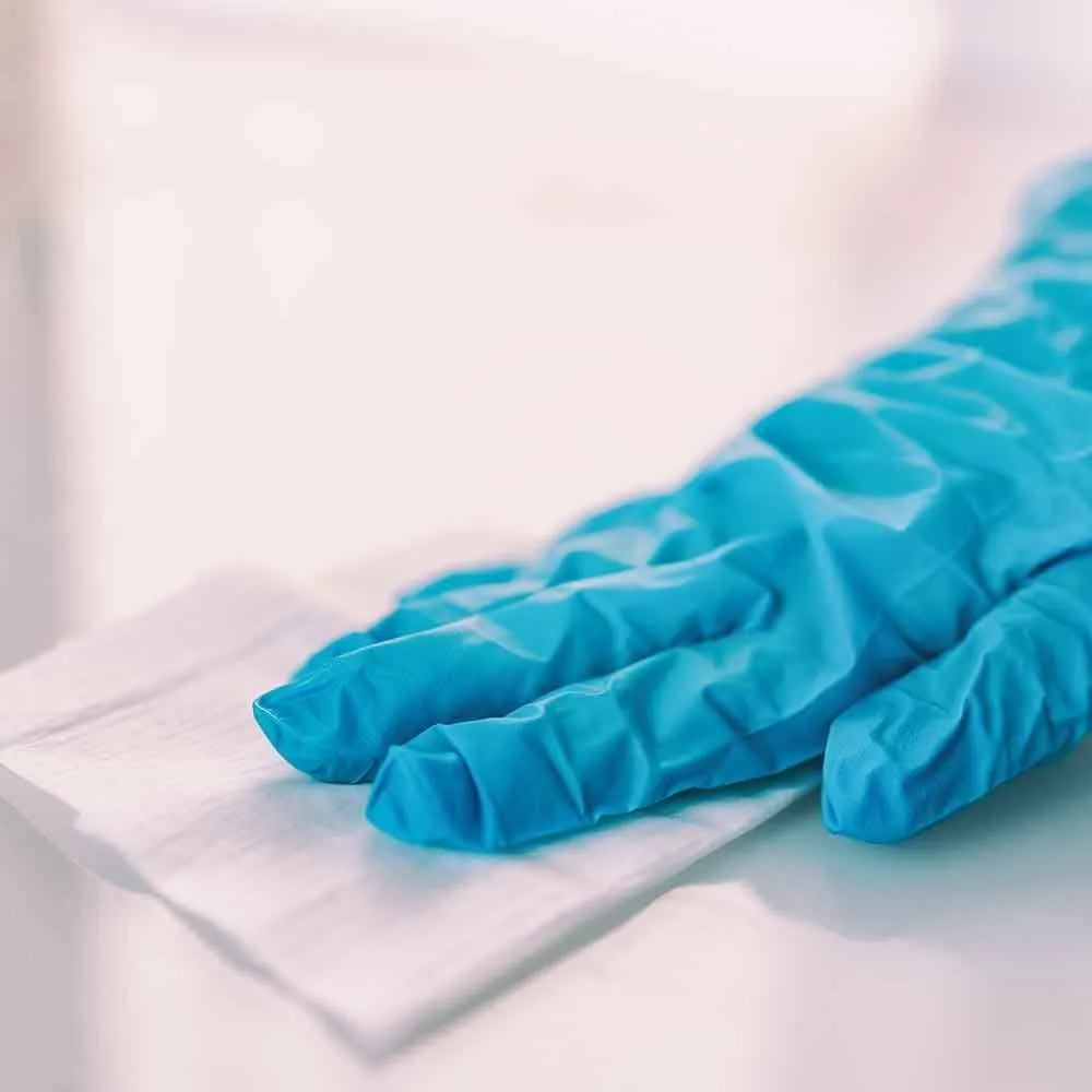 A person wearing a blue glove is holding a piece of paper.