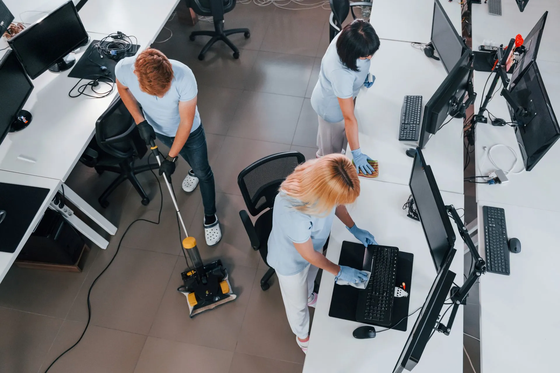 A group of people are cleaning an office with a vacuum cleaner.