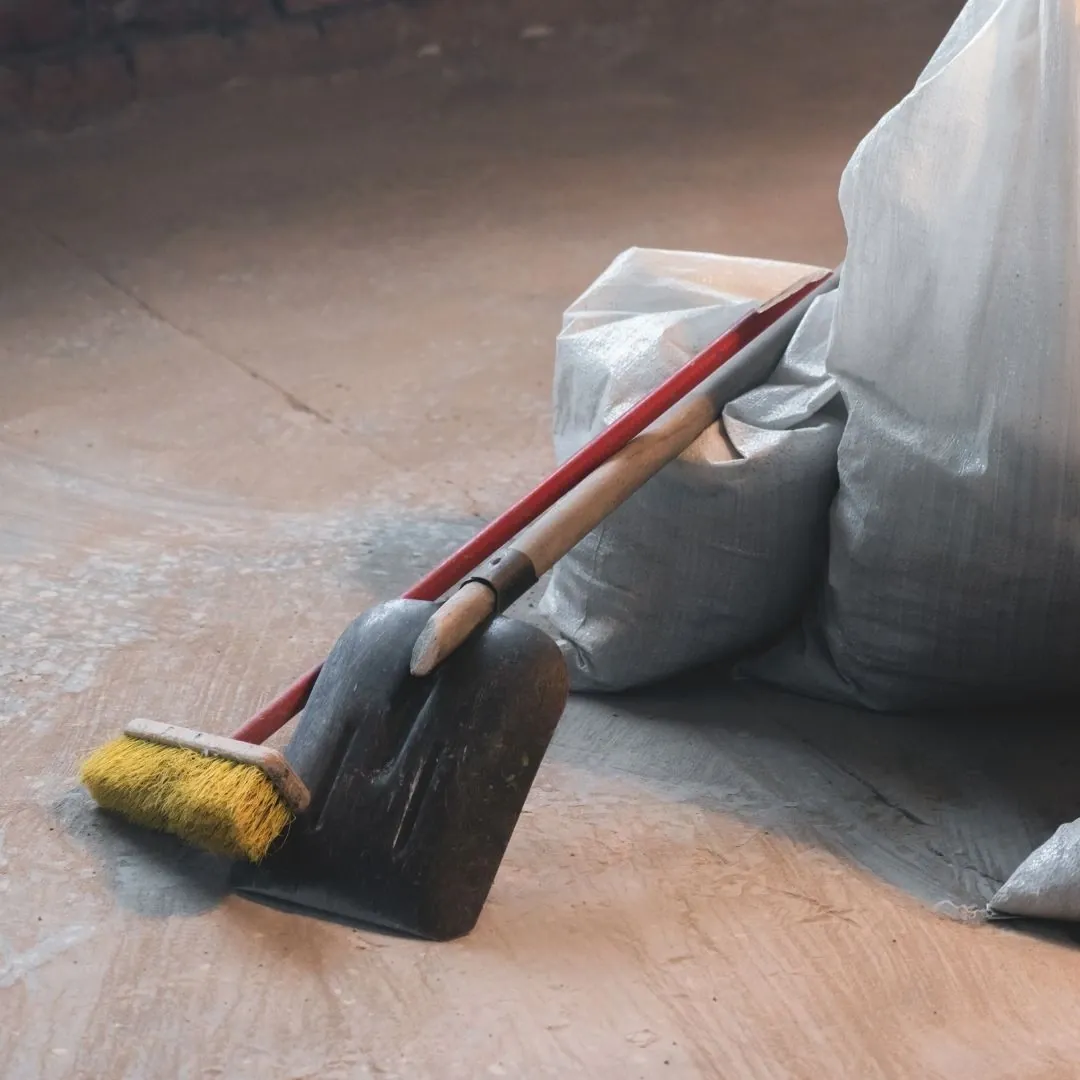 Push broom and shovel leaning on debris bags during post-construction cleaning in Greenville, SC