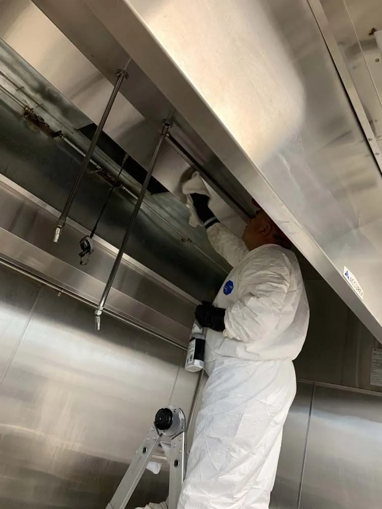 A man in a white suit is standing on a ladder under a ceiling.